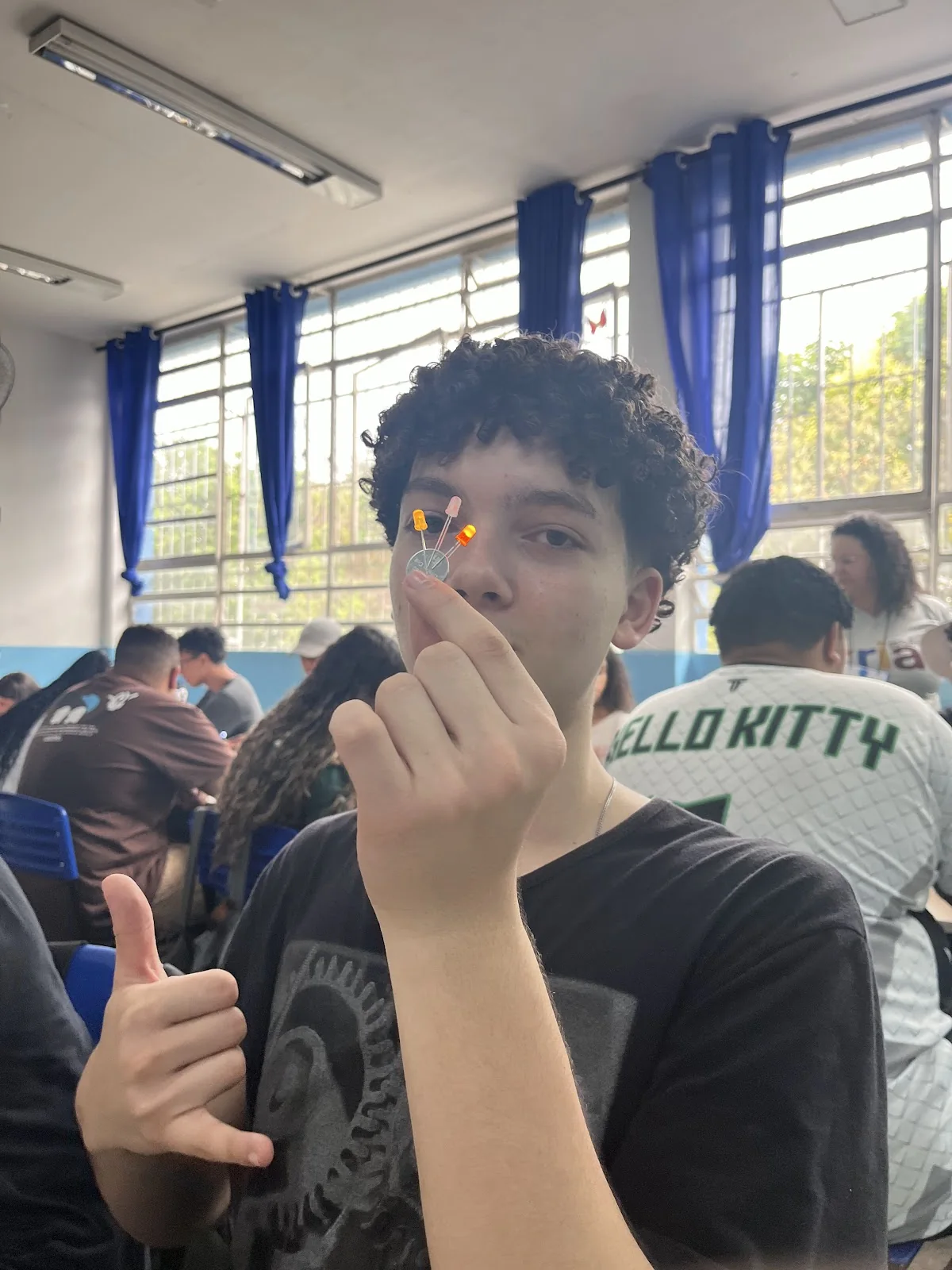 Estudante apresenta um pequeno circuito com LED aceso